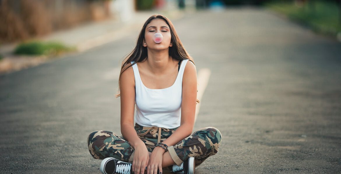 Girl is chewing gum sitting on the street