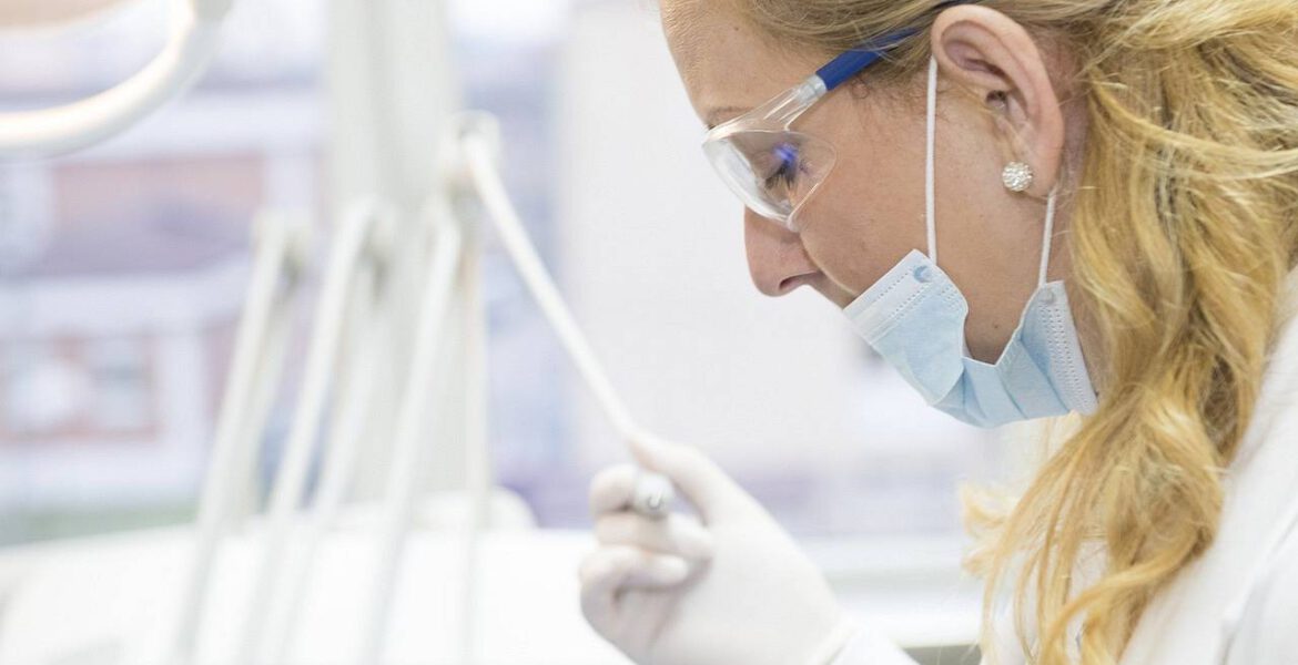 A dentist is treating man's teeth and she is enjoying her job as she is helping people to have healthy smiles